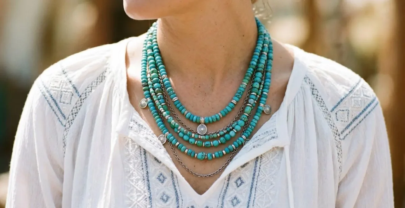 Femme portant un chemisier blanc brodé et un collier multi-rangs en turquoise et argent.