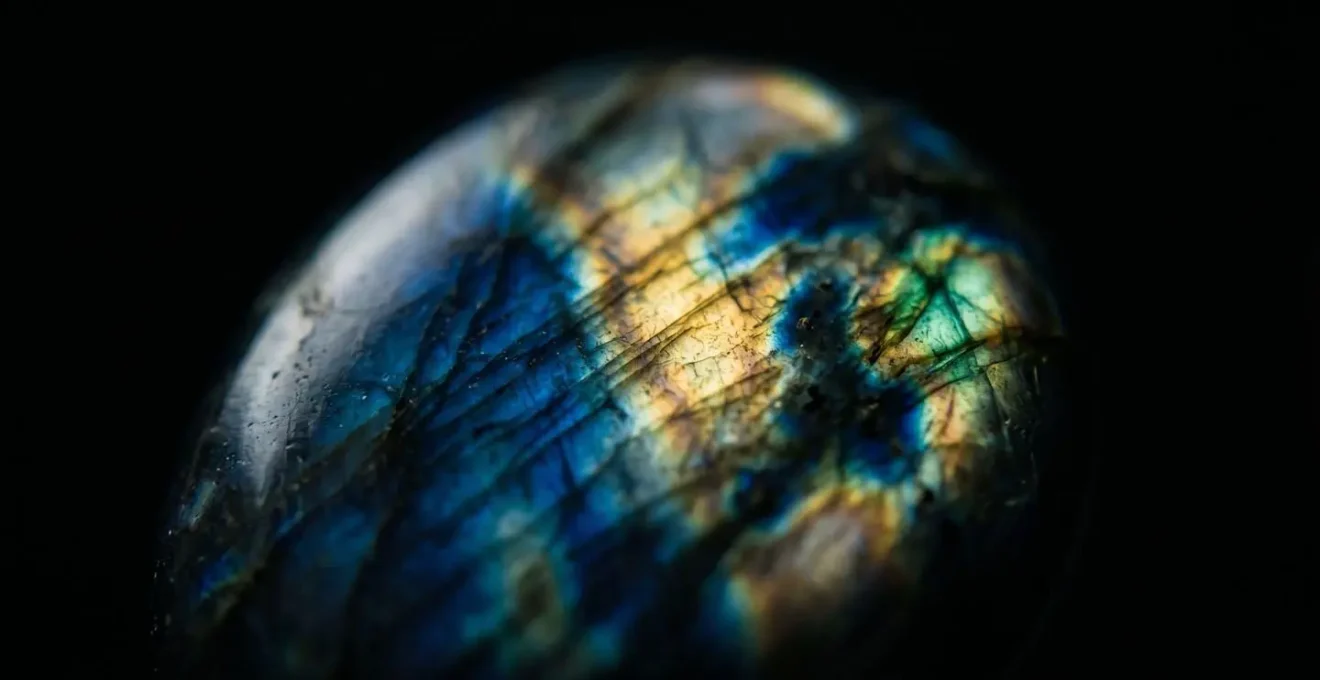 Gros plan sur une labradorite polie révélant des reflets irisés bleus, or et verts sur fond noir.